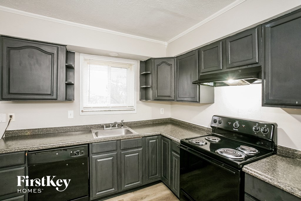 A kitchen with black cabinets and a black stove top oven.