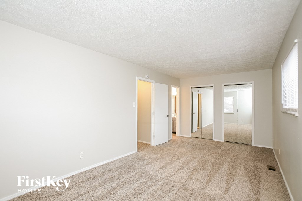 A carpeted room with a white ceiling and a window on the right wall.