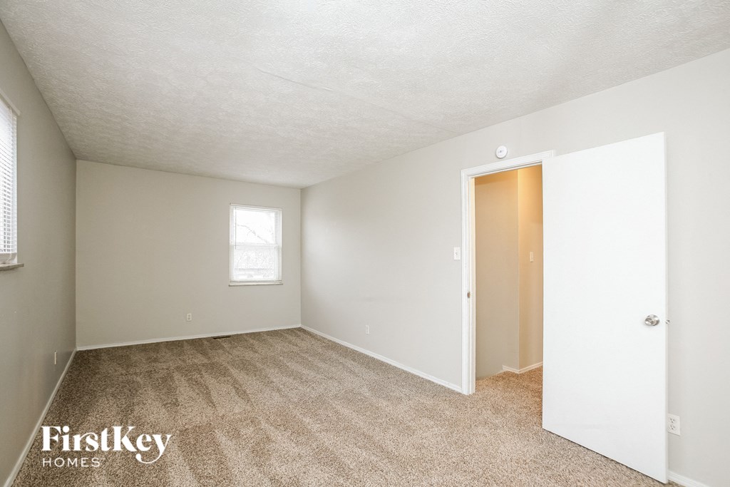 A room with a carpeted floor and a door leading to another room.
