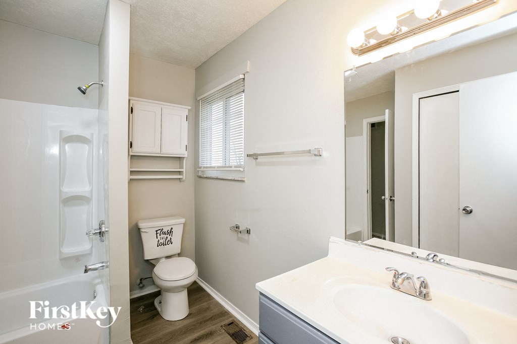 A white bathroom with a toilet, sink, and mirror.