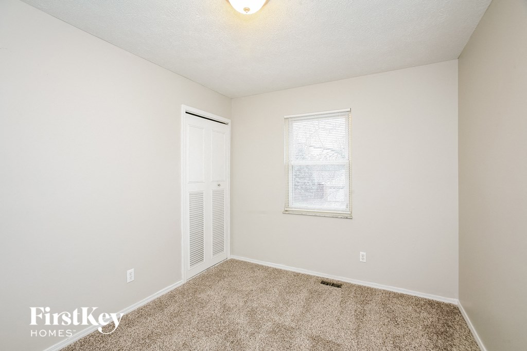 A carpeted room with a window and a door.