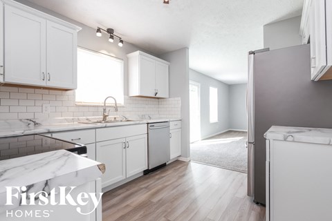 A kitchen with white cabinets and a marble countertop.
