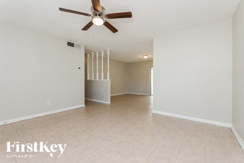 A spacious room with a ceiling fan and a doorway leading to another room.