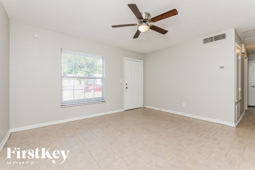 A room with a ceiling fan and a window with blinds.