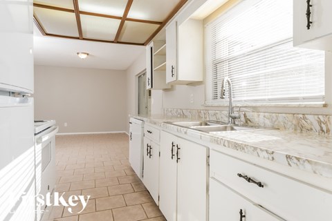 A kitchen with white cabinets and a marble countertop.
