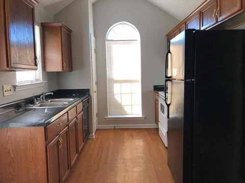 A kitchen with wooden cabinets and a black refrigerator.