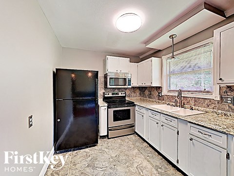 A kitchen with a black fridge, stove, and oven.
