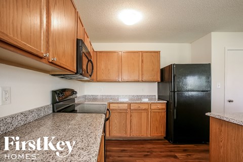 A kitchen with wooden cabinets and a black fridge.