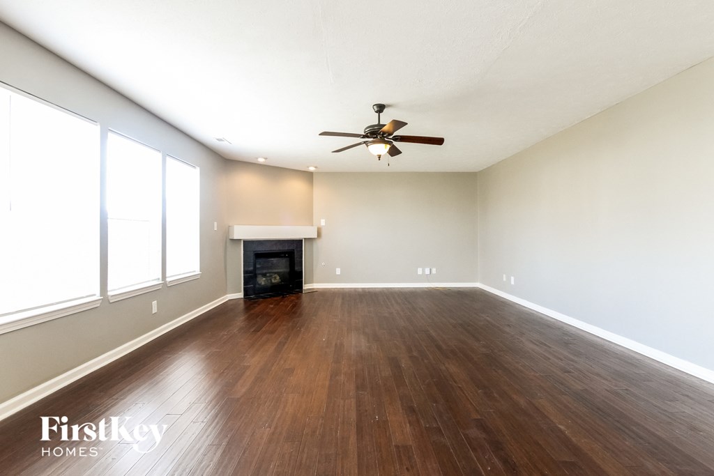 A spacious room with a fireplace and wood flooring.