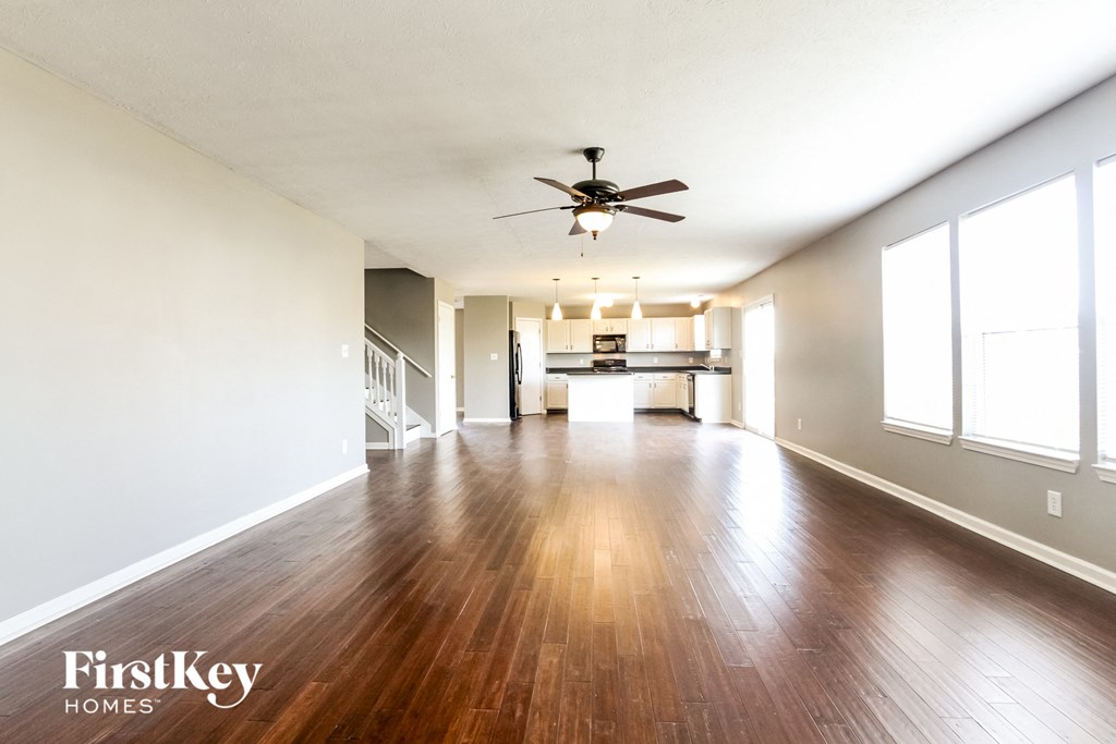 A spacious room with wooden floors and a ceiling fan.