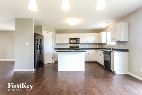 A kitchen with white cabinets and a black countertop.
