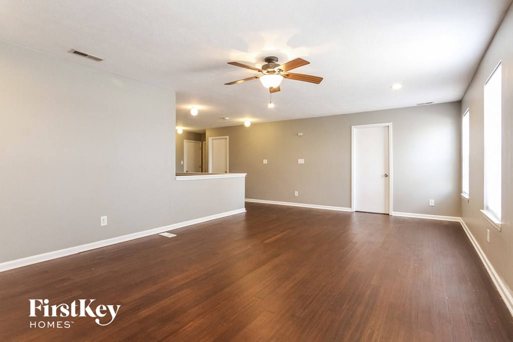 A spacious room with wooden floors and a ceiling fan.