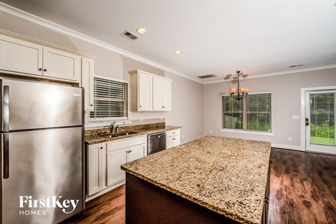 a kitchen with white cabinets and granite counter tops and a stainless steel refrigerator