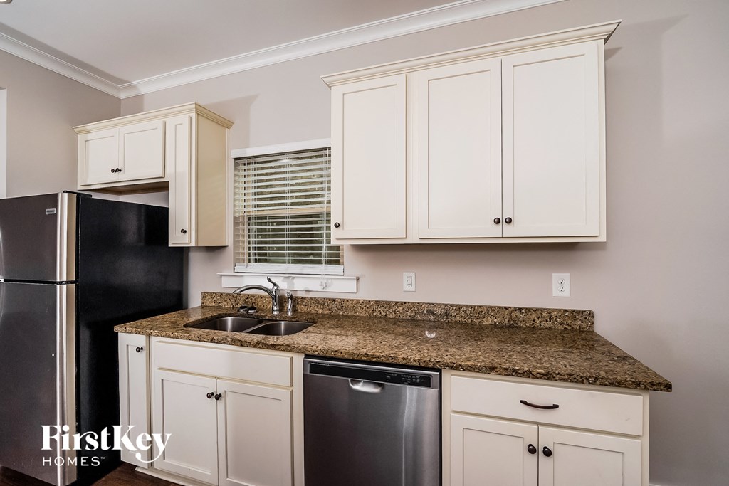 a kitchen with white cabinets and granite counter top and black appliances