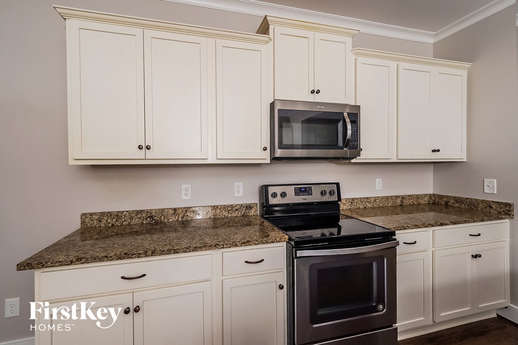 a kitchen with white cabinets and granite counter tops