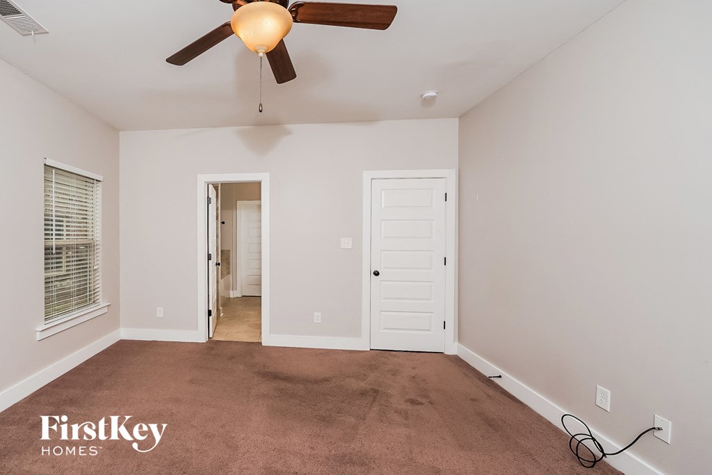 a empty living room with a ceiling fan and a white door
