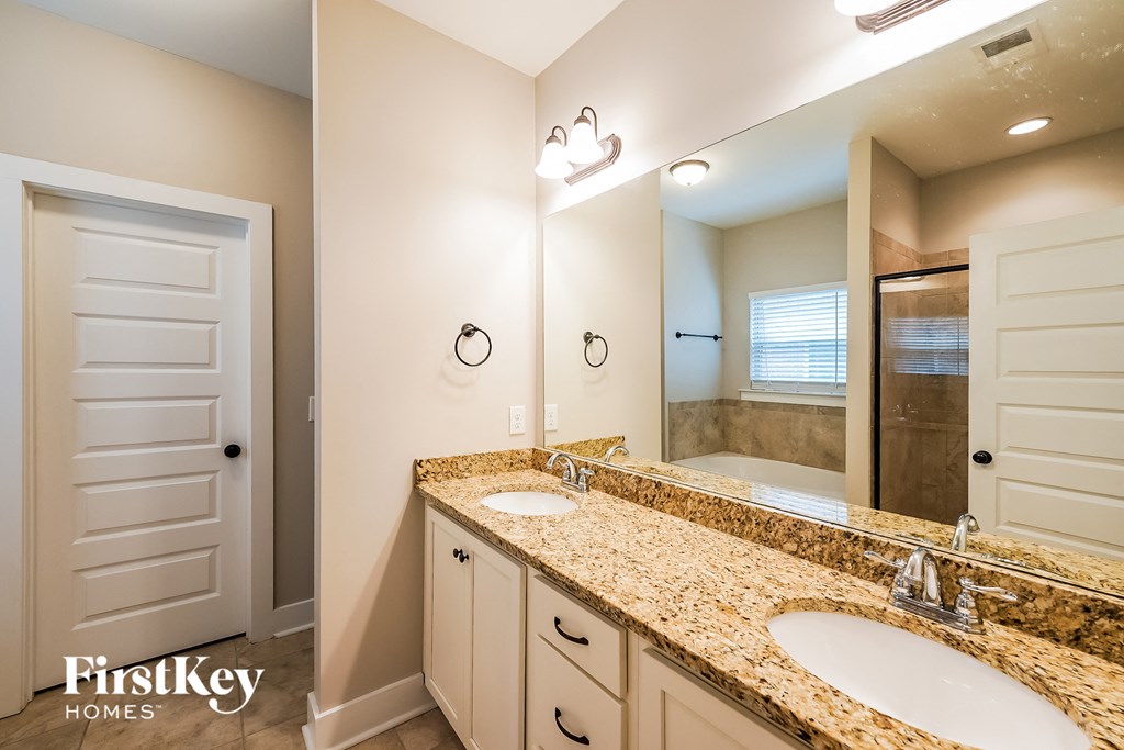 the master bathroom has dual sinks and a large mirror