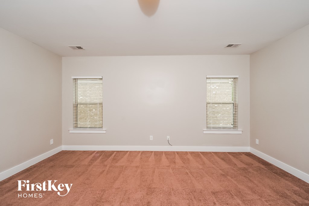 a spacious living room with wood floors and two windows