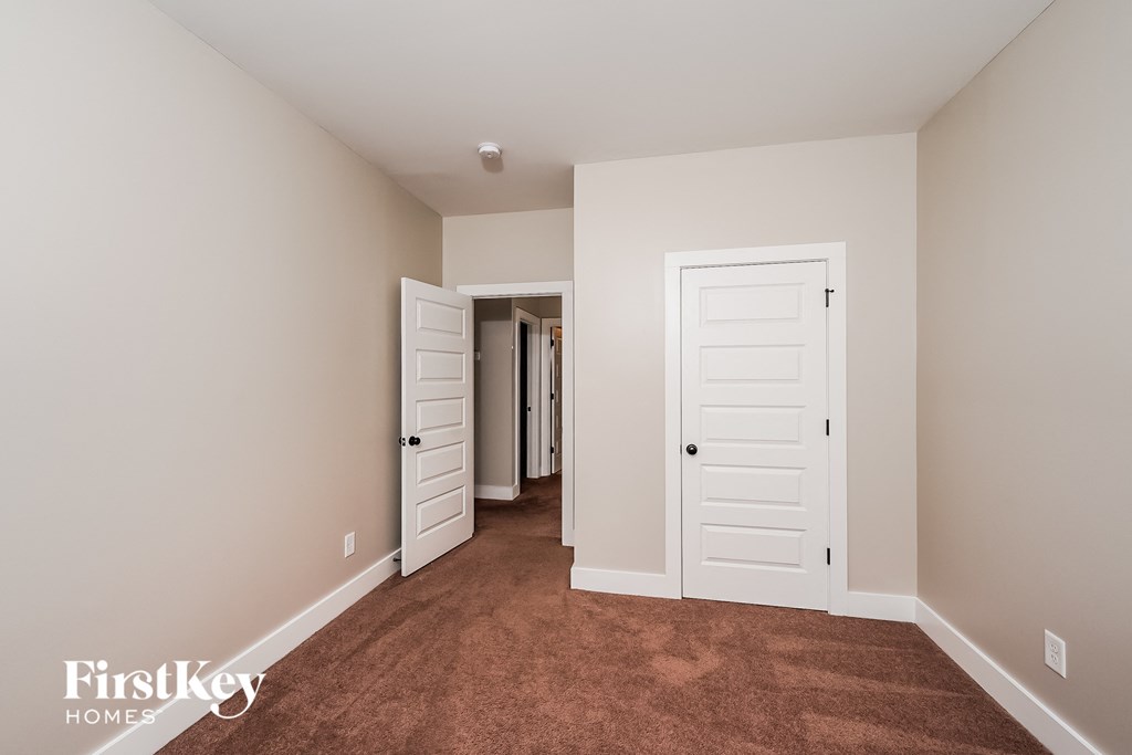 a bedroom with a carpeted floor and white closets and doors