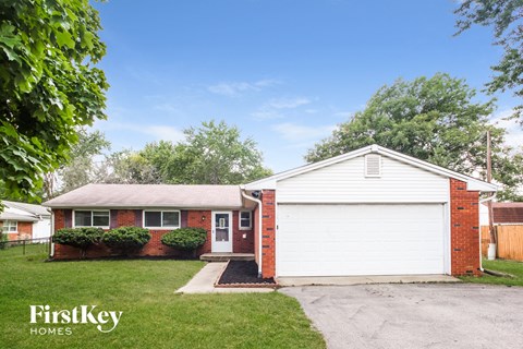 A house with a red brick exterior and a white garage door is for sale.
