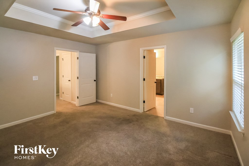 a empty living room with a ceiling fan and a closet