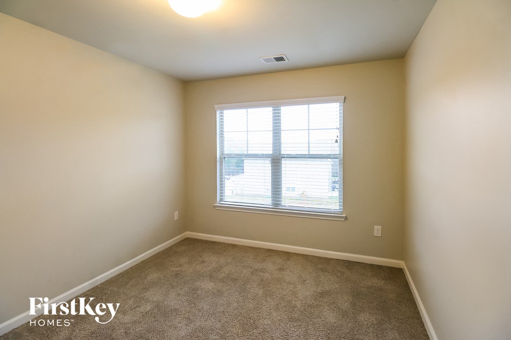 a carpeted room with a window and white walls