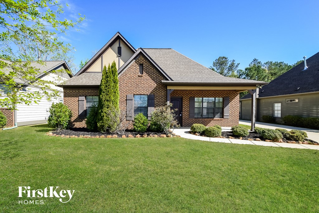 A house with a well-manicured lawn and a clear blue sky above.