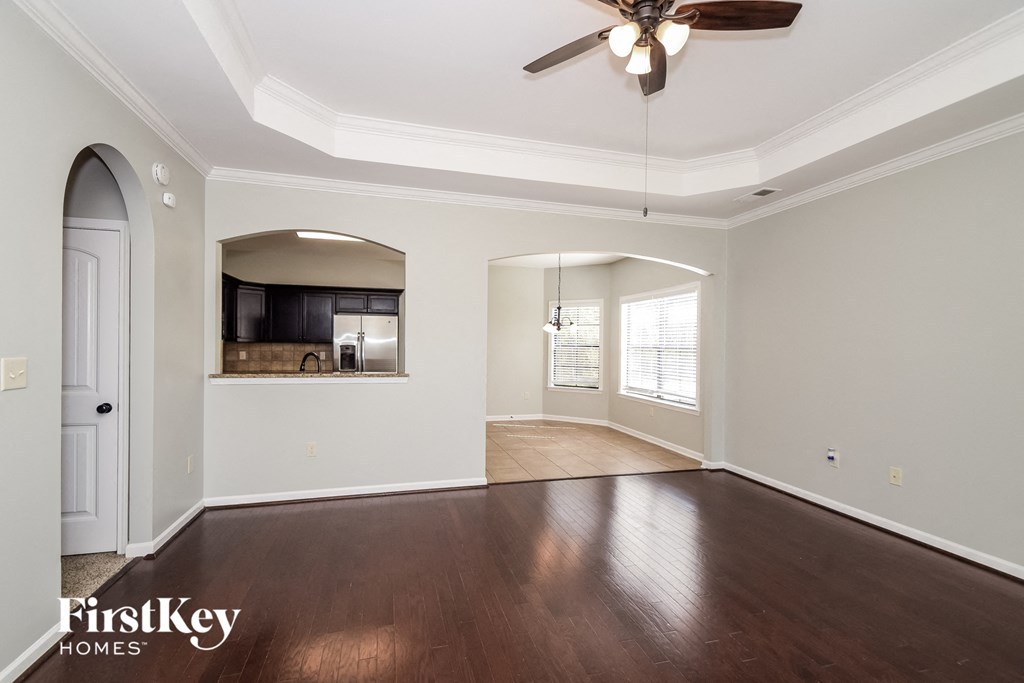 A spacious room with a ceiling fan and wooden flooring.