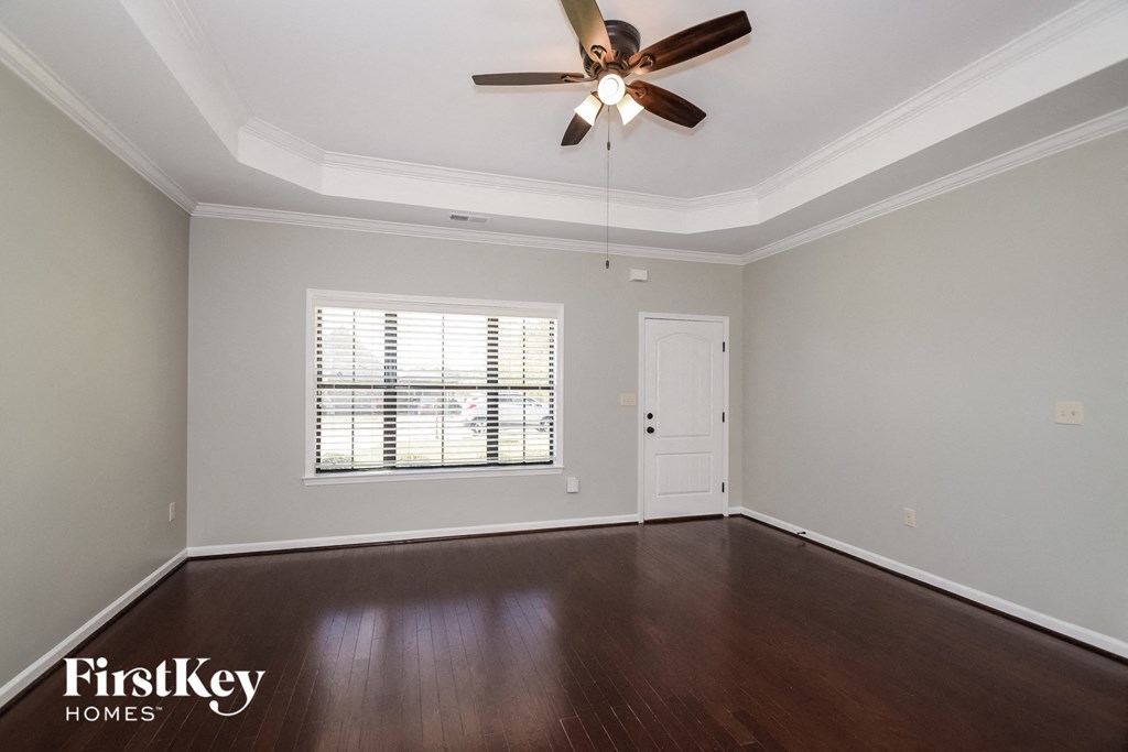 A room with a ceiling fan and wooden floors.