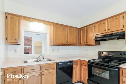 A kitchen with wooden cabinets and a black stove top oven.