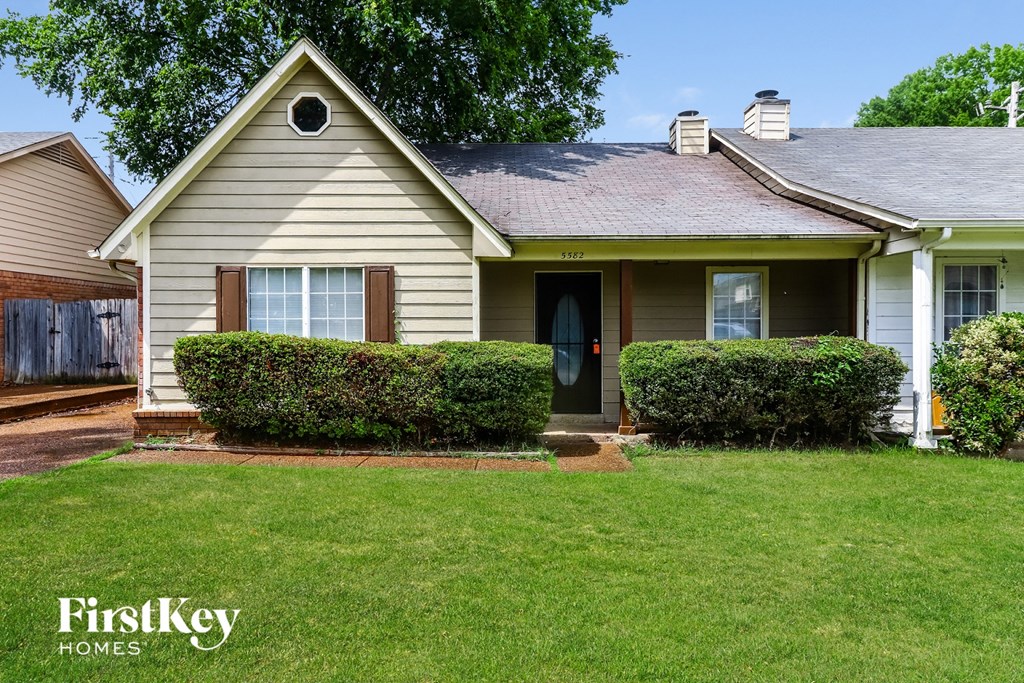 A house with a green lawn and a blue sky in the background.