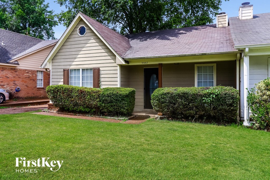 A house with a well-maintained lawn and a car parked in the driveway.
