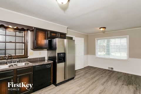 A kitchen with a refrigerator, sink, and cabinets.