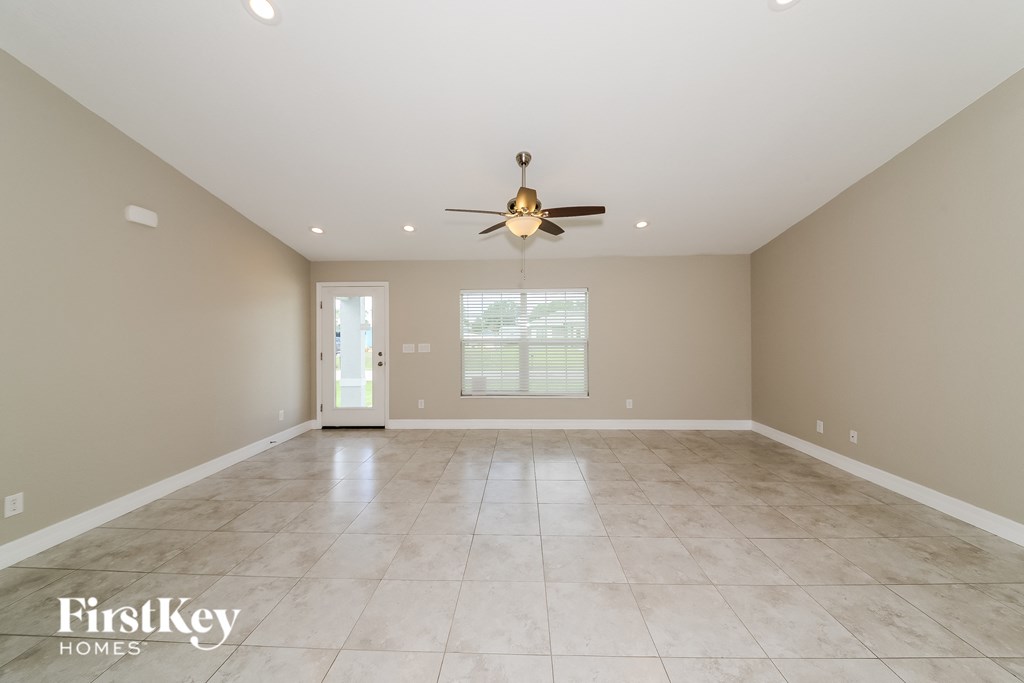 the spacious living room with travertine floors and a ceiling fan