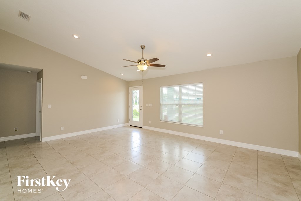 an empty living room with a ceiling fan and tiled floors