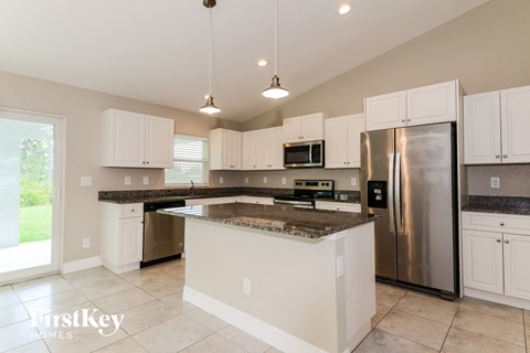 a kitchen with white cabinets and granite counter tops and a stainless steel refrigerator