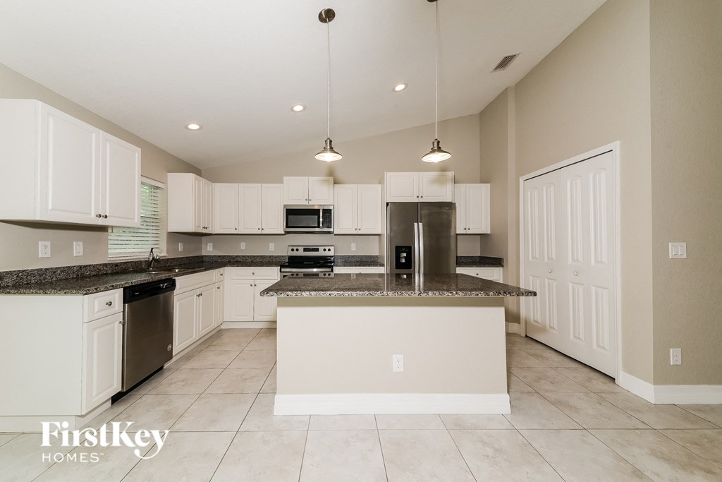 a large kitchen with white cabinets and granite counter tops