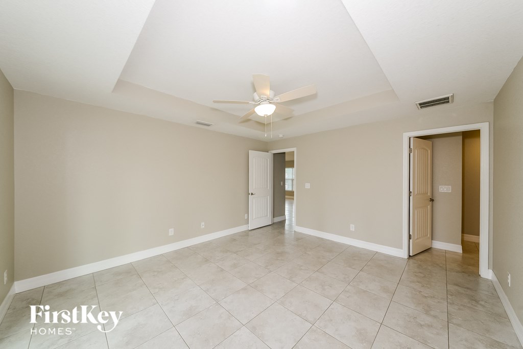 a spacious living room with tile flooring and a ceiling fan