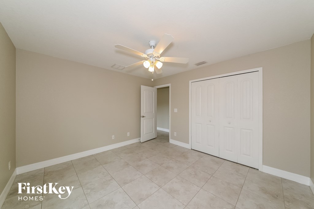 the spacious living room with ceiling fan and tile flooring