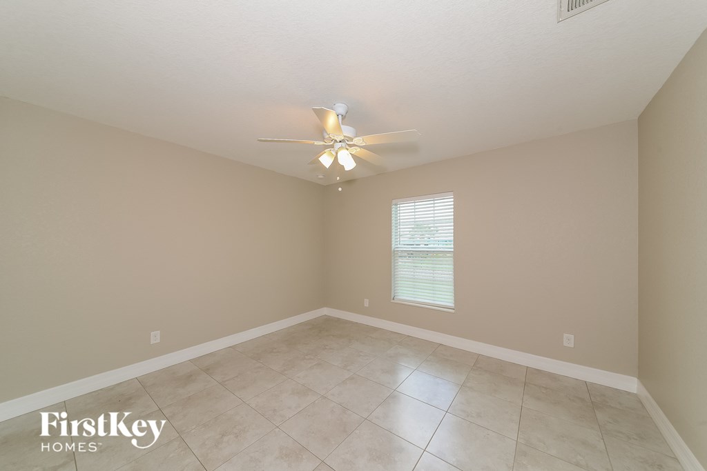 an empty living room with a ceiling fan and a tiled floor
