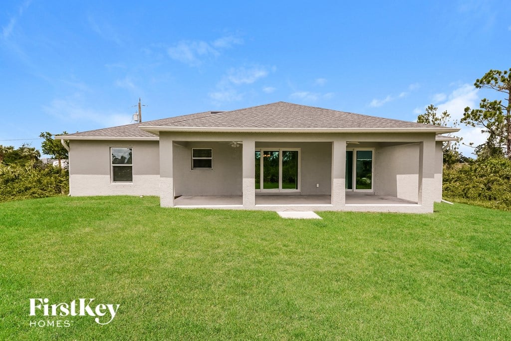 a small tan house with a grassy lawn and a blue sky