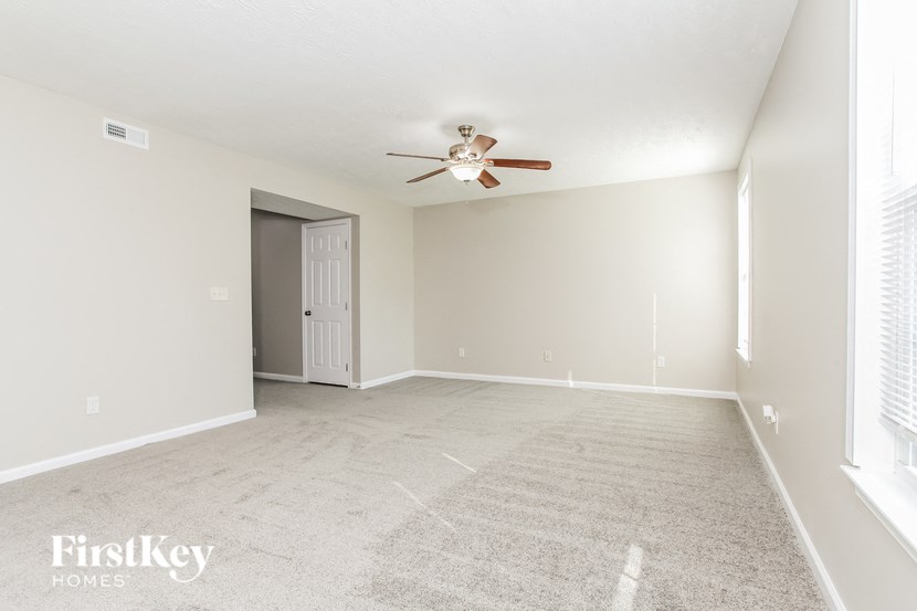 A spacious room with a ceiling fan and a door leading to another room.