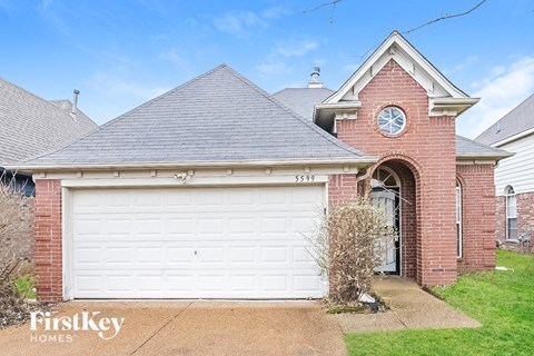 A brick house with a white garage door and a clock on the wall.