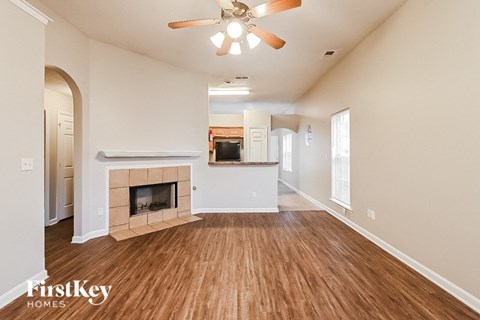 A spacious living room with a fireplace and a ceiling fan.