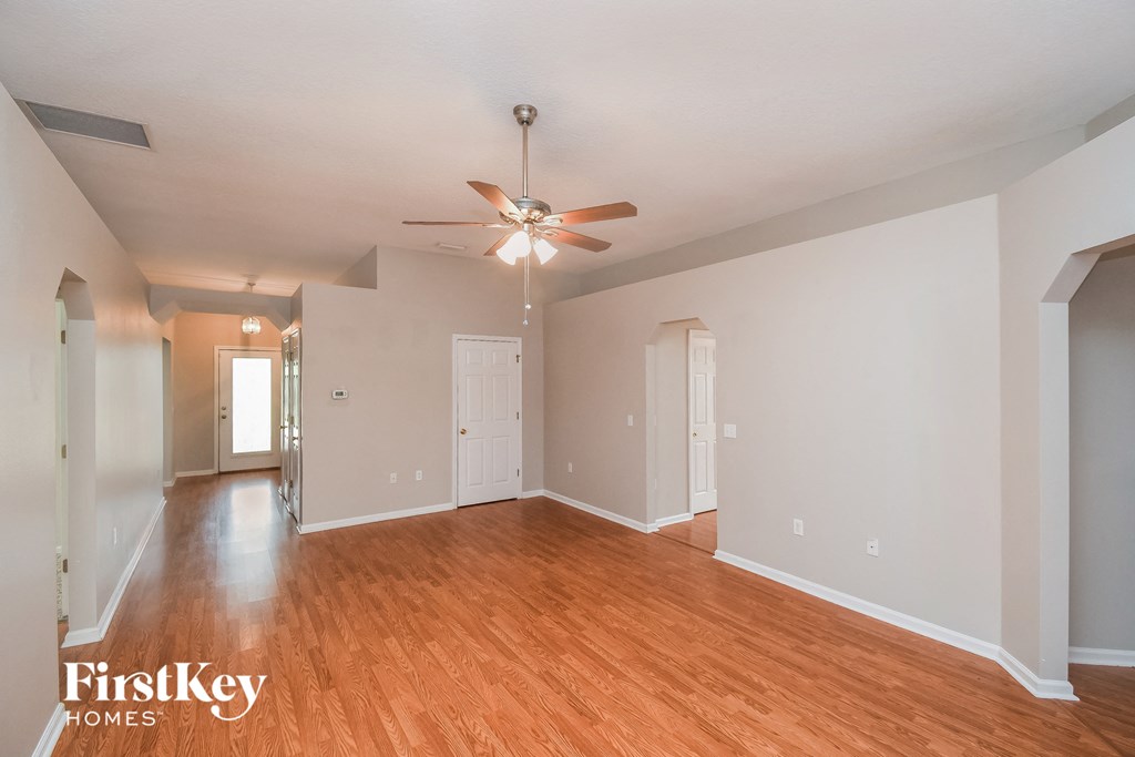 the living room and dining room of an empty house with a ceiling fan