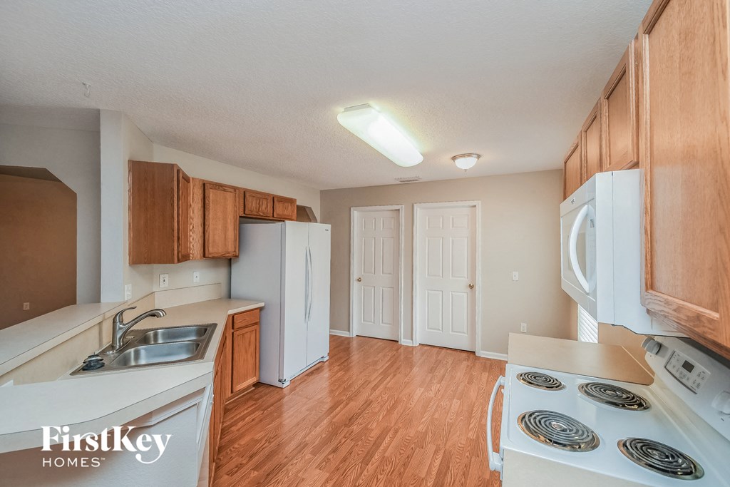a kitchen with white appliances and wood flooring and a white refrigerator