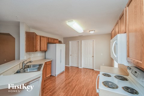 a kitchen with white appliances and wood flooring and a white refrigerator