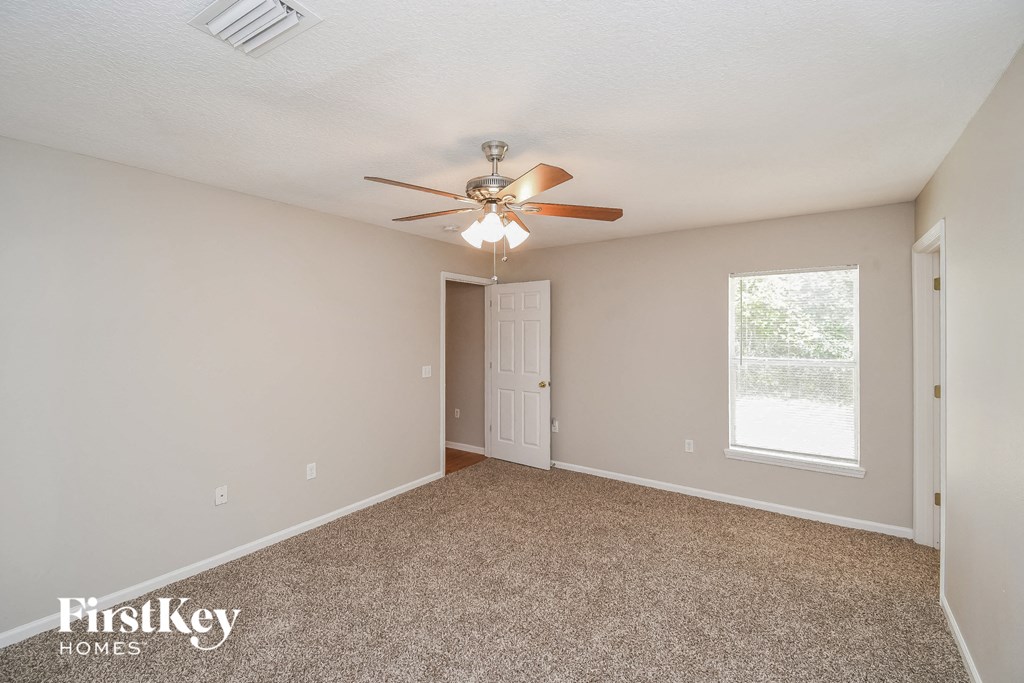 the spacious living room with ceiling fan and carpeting