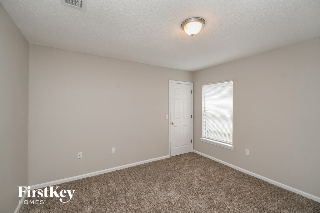a bedroom with a door and a window and a carpeted floor
