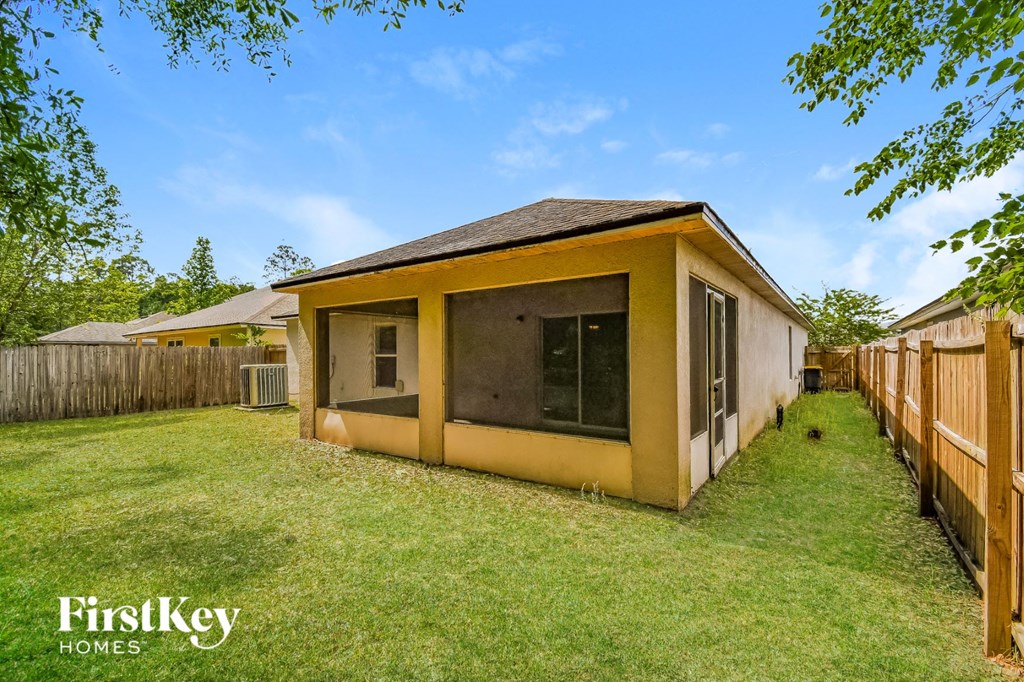 a backyard with a small yellow house and a backyard fence